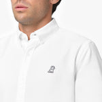 Close-up detail of the white oxford shirt collar and chest area on a male model, showing the button-down collar, buttons, fabric texture, and the small black embroidered dog logo on the left chest
