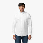 Front waist-up view of a male model wearing a white long-sleeve button-down oxford shirt with a small white embroidered logo on the left chest, paired with dark wash jeans
