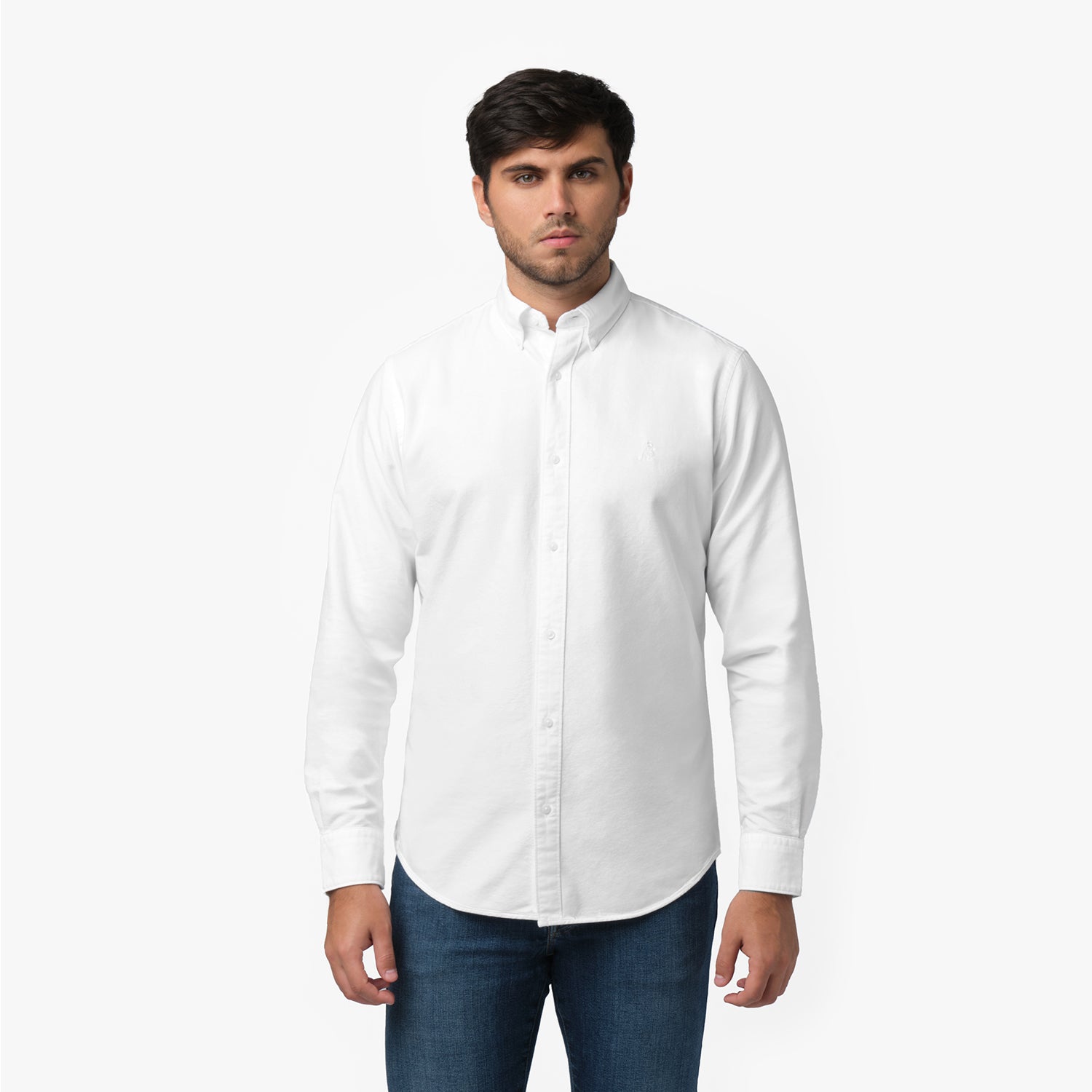 Front waist-up view of a male model wearing a white long-sleeve button-down oxford shirt with a small white embroidered logo on the left chest, paired with dark wash jeans
