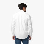 Back waist-up view of a male model wearing a white long-sleeve oxford shirt with a back pleat, paired with dark wash jeans