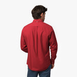 Back waist-up view of a male model wearing a red long-sleeve oxford shirt with a back pleat, paired with blue trousers
