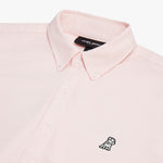 Close-up of the collar and upper chest area of a light pink button-down shirt. Features include a button-down collar, white buttons, a black "JAMES BARK" brand tag, and a black-and-white embroidered dog logo on the left chest