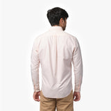 Back waist-up view of a male model wearing a light pink long-sleeve oxford shirt with a back pleat, paired with brown trousers
