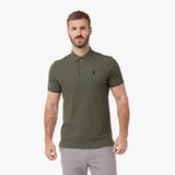A man wearing an olive green polo shirt with a small dark embroidered logo on the left chest
