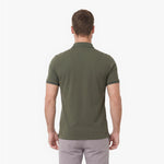A man viewed from behind wearing an olive green polo shirt and light gray trousers