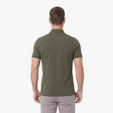 A man viewed from behind wearing an olive green polo shirt and light gray trousers