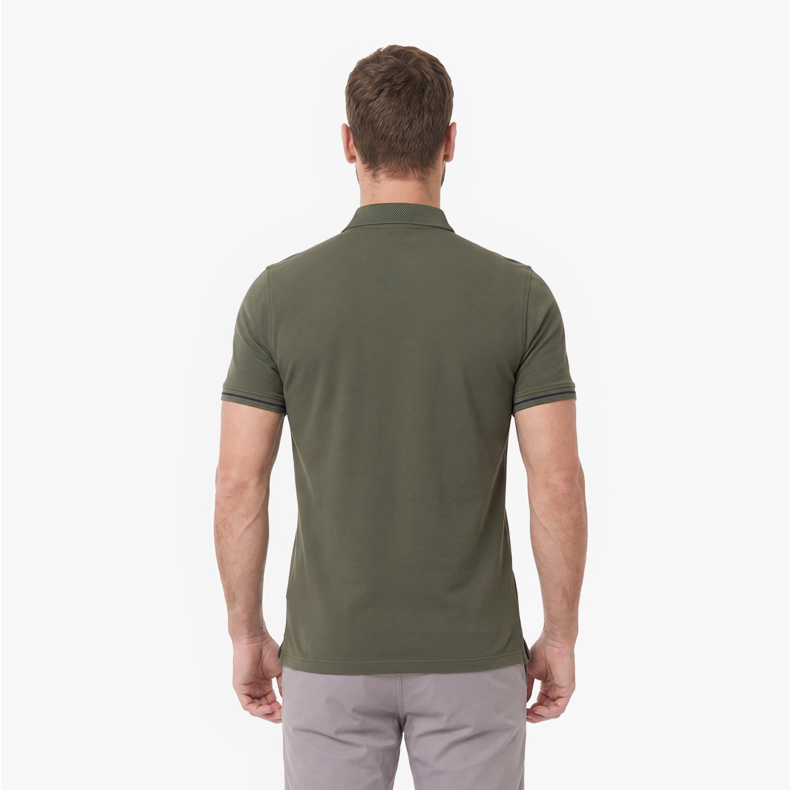 A man viewed from behind wearing an olive green polo shirt and light gray trousers