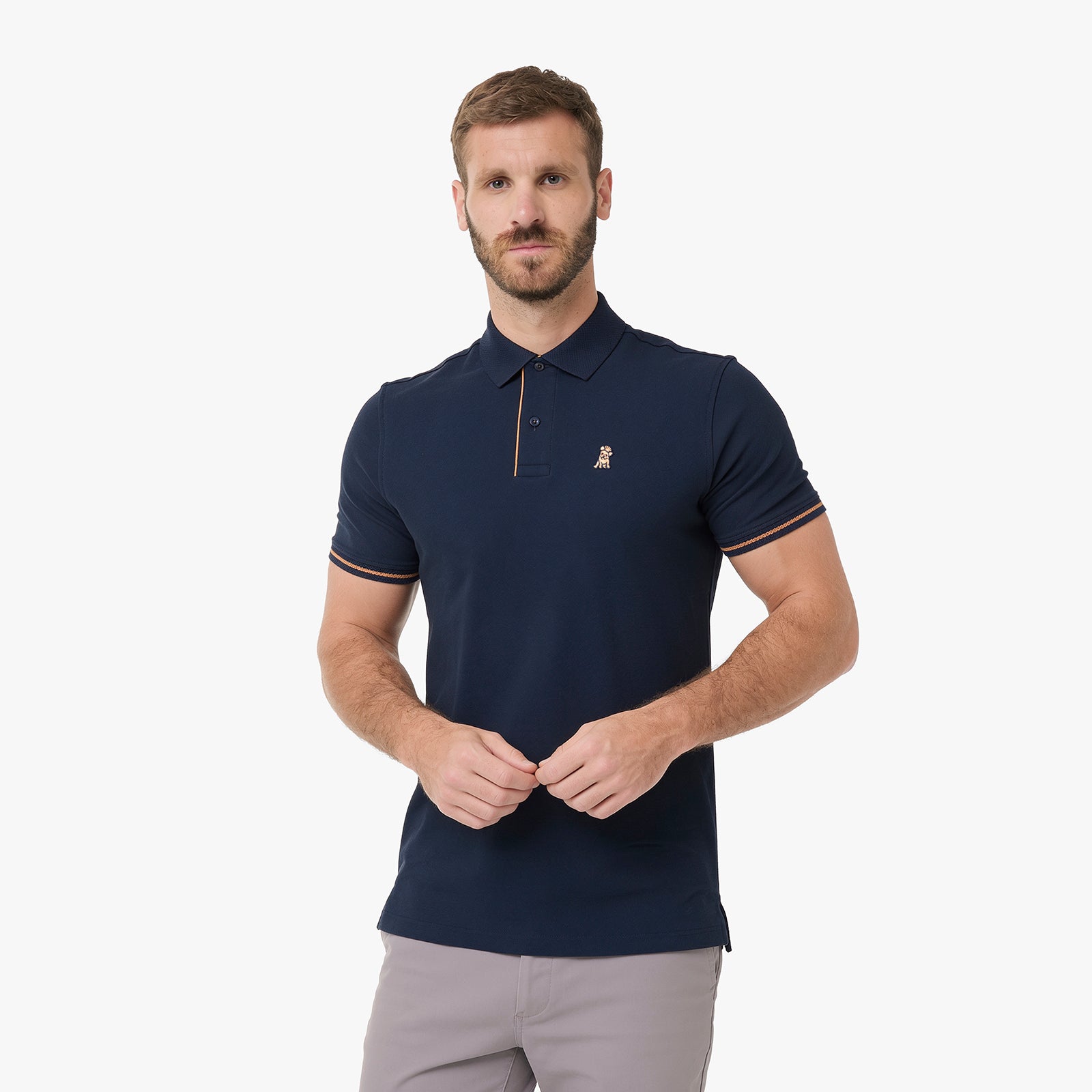 A man wearing a navy blue polo shirt with gold trim and a small embroidered logo on the chest