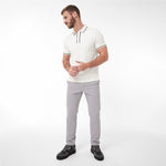 A man wearing a white short-sleeve polo shirt with black trim, light gray trousers, and black sneakers
