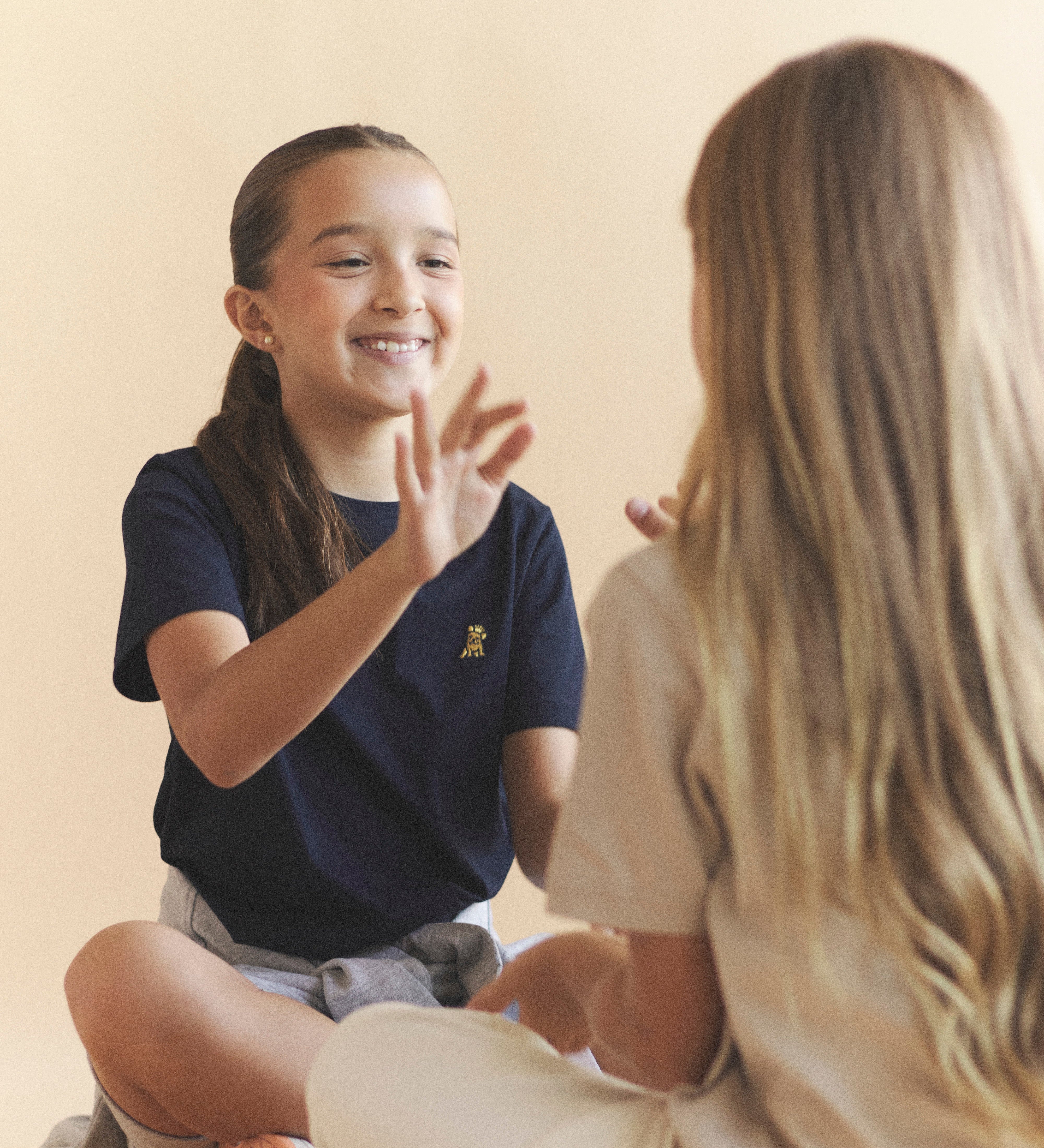 Two children sitting on the floor, smiling and interacting with each other.