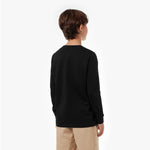 Back view of a young boy wearing a black long-sleeved t-shirt and tan shorts