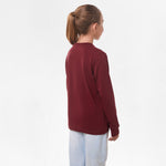 Side view of the girl wearing the burgundy long-sleeve shirt, showing the plain back and the relaxed fit.