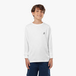 Young boy wearing a white long-sleeved t-shirt with a small dog logo and navy shorts, standing front view