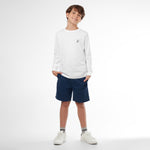 Full picture of a young boy wearing a white long-sleeved t-shirt with a small dog logo and navy shorts, standing front view