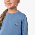 Close-up of the chest area of the light blue shirt, featuring the small embroidered logo.