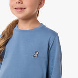 Close-up of the chest area of the light blue shirt, featuring the small embroidered logo.