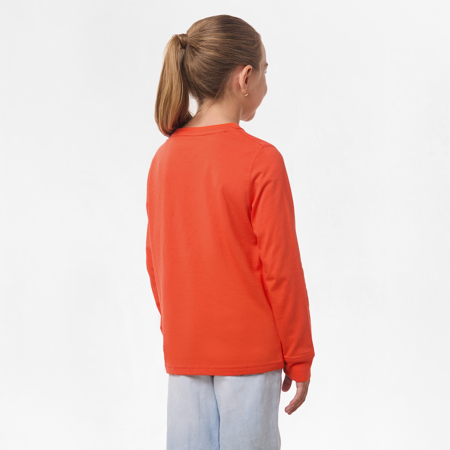 Side view of the girl wearing the orange long-sleeve shirt, showing the plain back and relaxed fit.