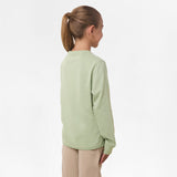 Side view of the girl wearing the light green long-sleeve shirt, showing the plain back and relaxed fit.