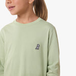 Close-up of the chest area of the light green shirt, featuring the small embroidered logo.