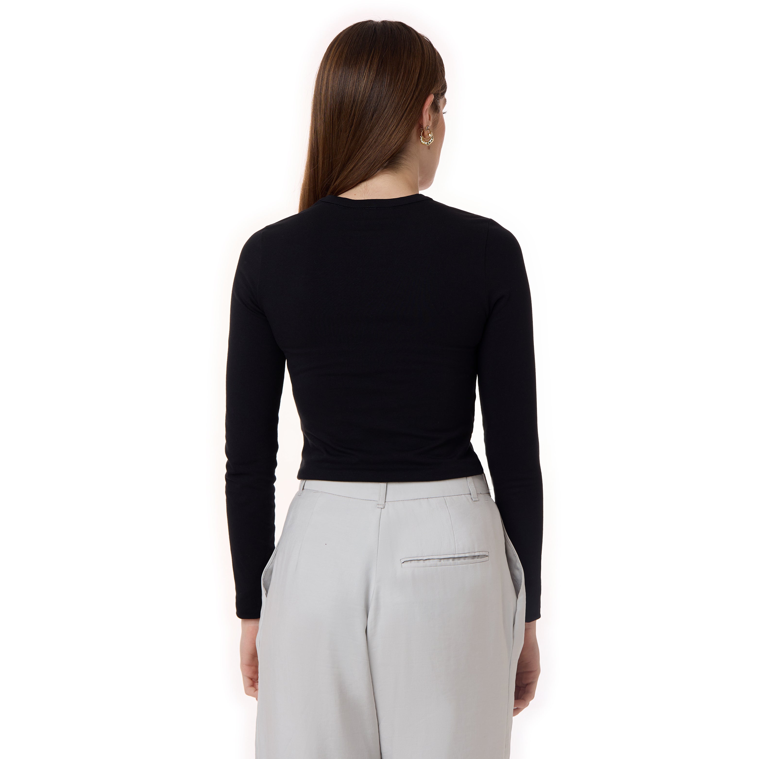 A back view of the outfit, showcasing the black top's fitted design and the light gray trousers with a single back pocket. The model's long hair and minimal styling complement the clean look.