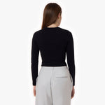 A back view of the outfit, showcasing the black top's fitted design and the light gray trousers with a single back pocket. The model's long hair and minimal styling complement the clean look.