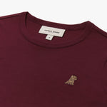 Close-up of the neckline and small dog graphic on the chest of the burgundy long-sleeve shirt.