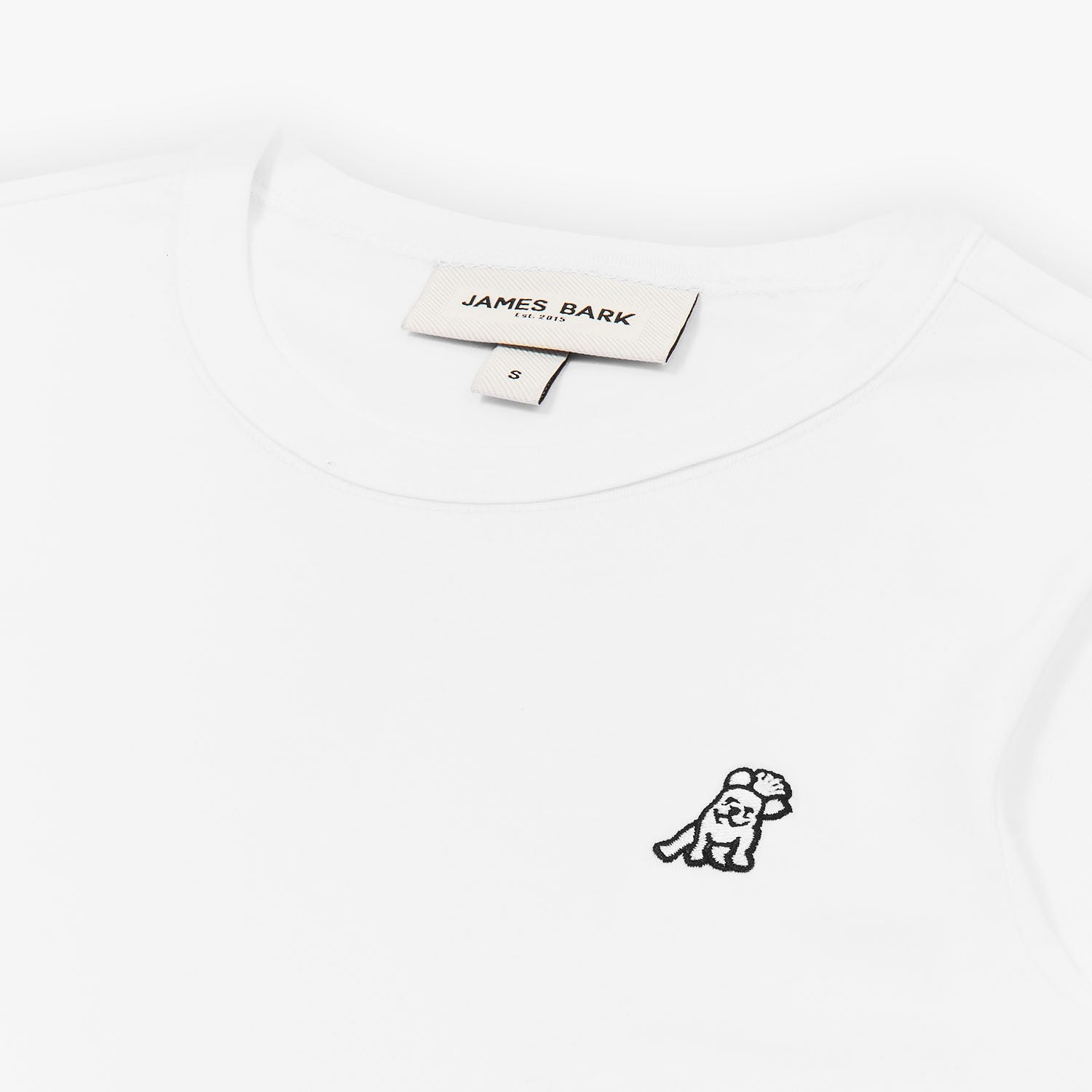 Close-up of the neckline and small dog graphic on the chest of the white long-sleeve shirt.