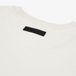 Close-up of the back of a white t-shirt, highlighting a black rectangular 'JAMES BARK' label near the neckline. The fabric appears soft with a ribbed collar and a minimalist aesthetic. White background