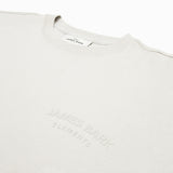 Close-up of a white t-shirt featuring an embossed 'JAMES BARK ELEMENTS' logo on the chest. The fabric appears soft, with a ribbed crew neck collar and a minimalist design. White background