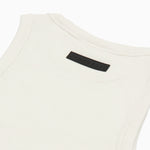 Close-up of the back of a white ribbed tank top, highlighting a black rectangular 'JAMES BARK' label near the neckline. The fabric has a textured ribbed pattern with reinforced stitching along the edges. White background