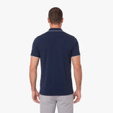 Back view of a man wearing a navy blue polo on a white background