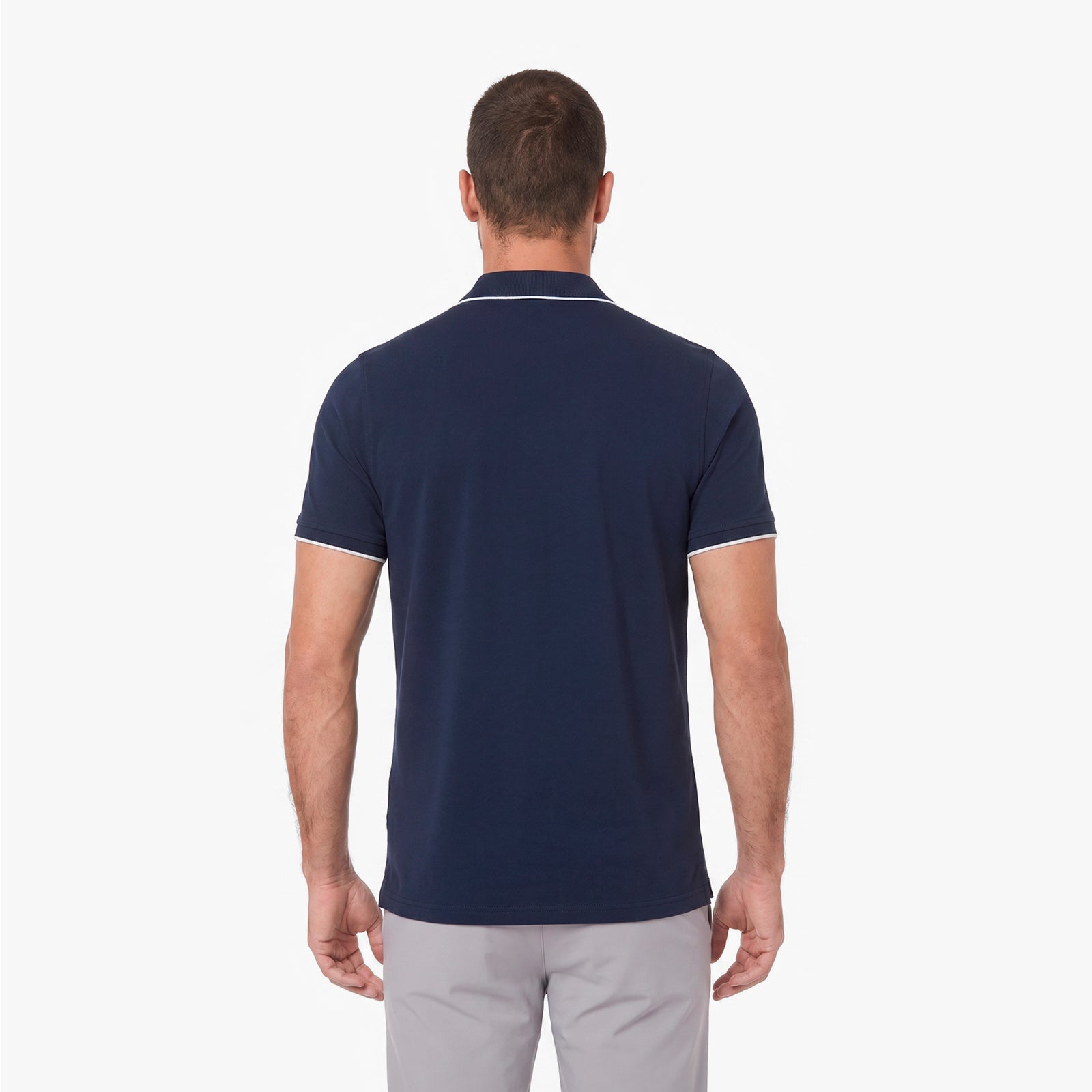 Back view of a man wearing a navy blue polo on a white background