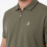 Close-up of a man wearing an olive green short-sleeve polo shirt with a half-zip collar and a small embroidered dog logo on the chest.