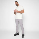 A man modeling a white short-sleeve polo shirt and light gray trousers with black sneakers