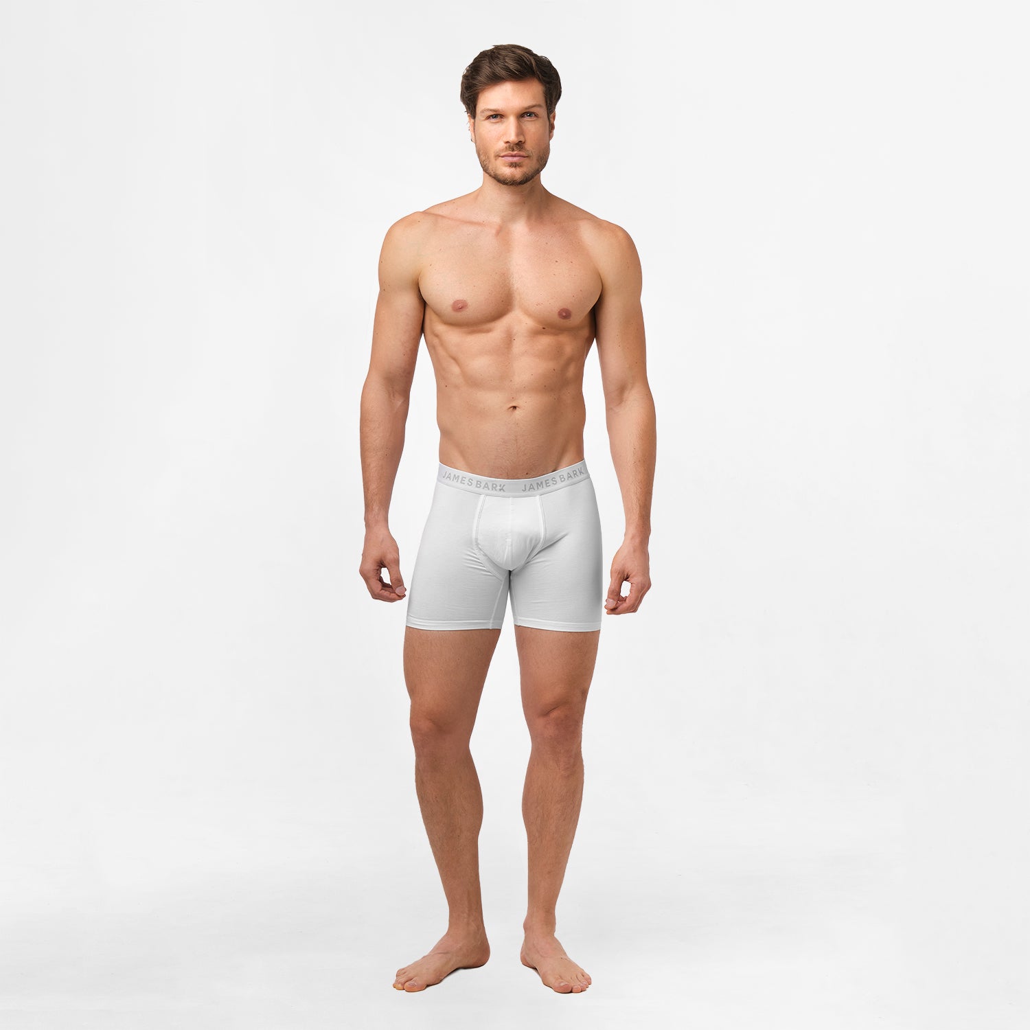 A male model wearing white James Bark boxer briefs. The briefs have a fitted design with 'JAMES BARK' branding on the waistband, which sits comfortably at the waist. The model is standing straight with a neutral expression.