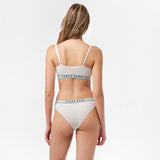 Rear view of a woman wearing the white bralette and underwear set, showing the back design.