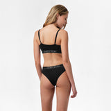 Rear view of a woman wearing the black bralette and underwear set, showing the back design.
