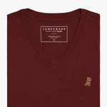 Close-up view of the burgundy V-neck t-shirt laid flat, highlighting the collar and small embroidered logo.