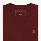 Close-up view of the burgundy V-neck t-shirt laid flat, highlighting the collar and small embroidered logo.