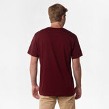 Rear view of the man wearing the burgundy V-neck t-shirt, showing the plain back design, paired with beige pants.