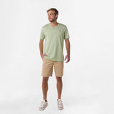 Full-body shot of the man wearing the mint green V-neck t-shirt and beige shorts, standing with his hands relaxed by his sides.