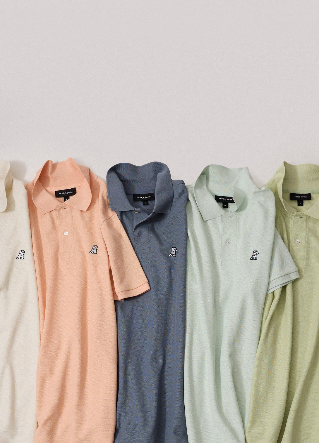 Five short-sleeve polo shirts in soft pastel colors are arranged side by side. The colors are cream, peach, slate blue, pale mint, and light olive green.