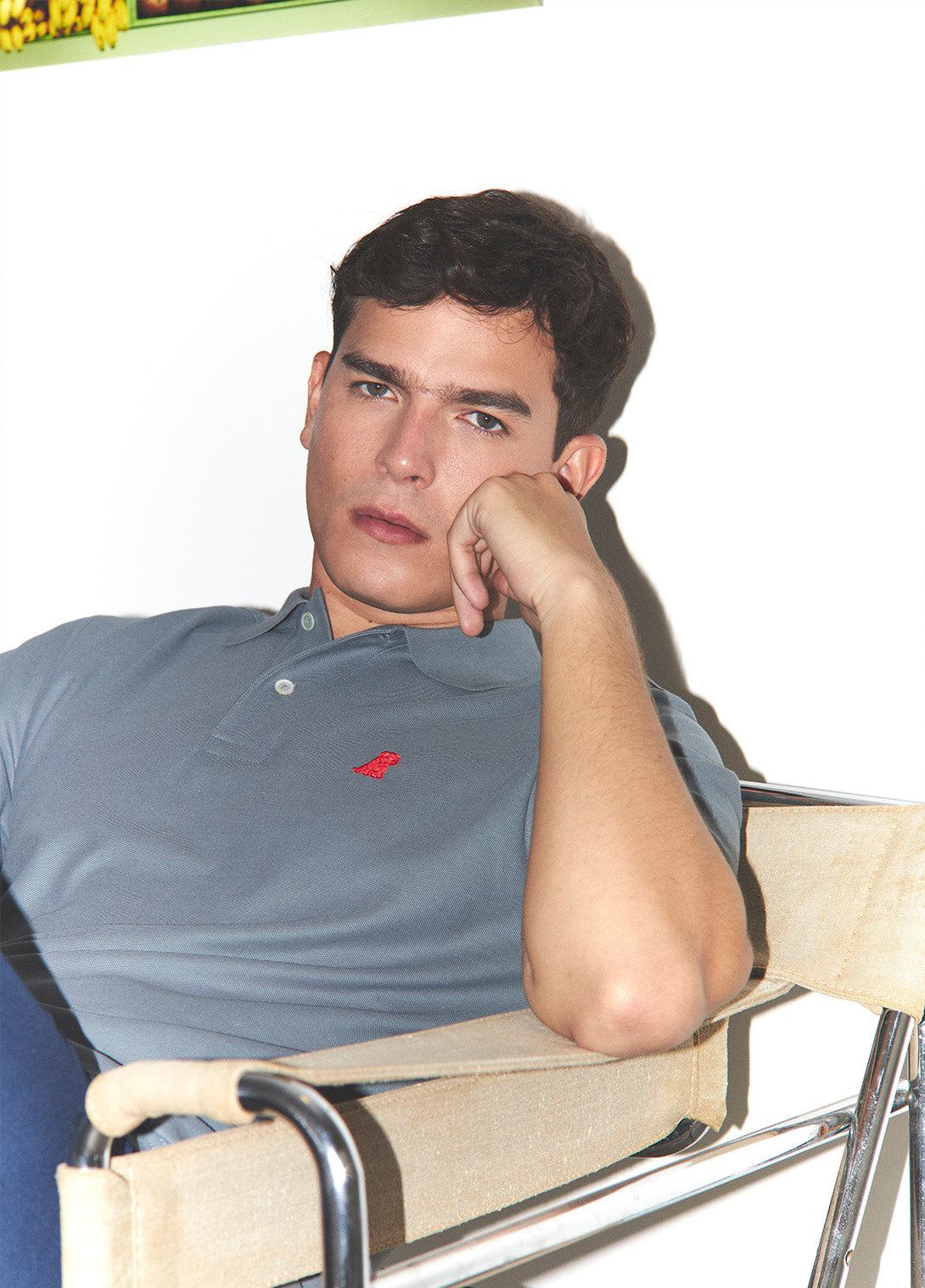 Man sitting on a director's chair with a neutral background