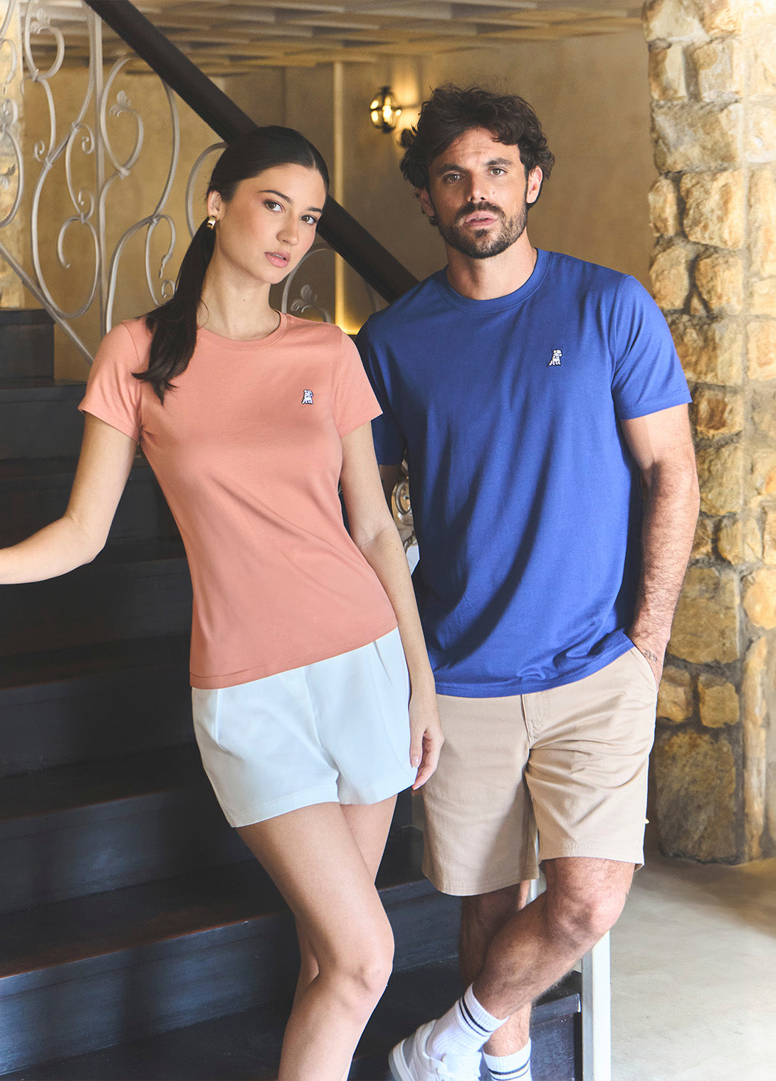Man and woman standing on a staircase wearing matching t-shirts and shorts.