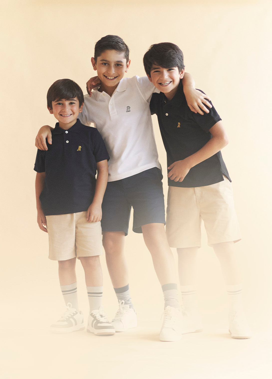 Three children wearing matching outfits with a brand logo on a plain background