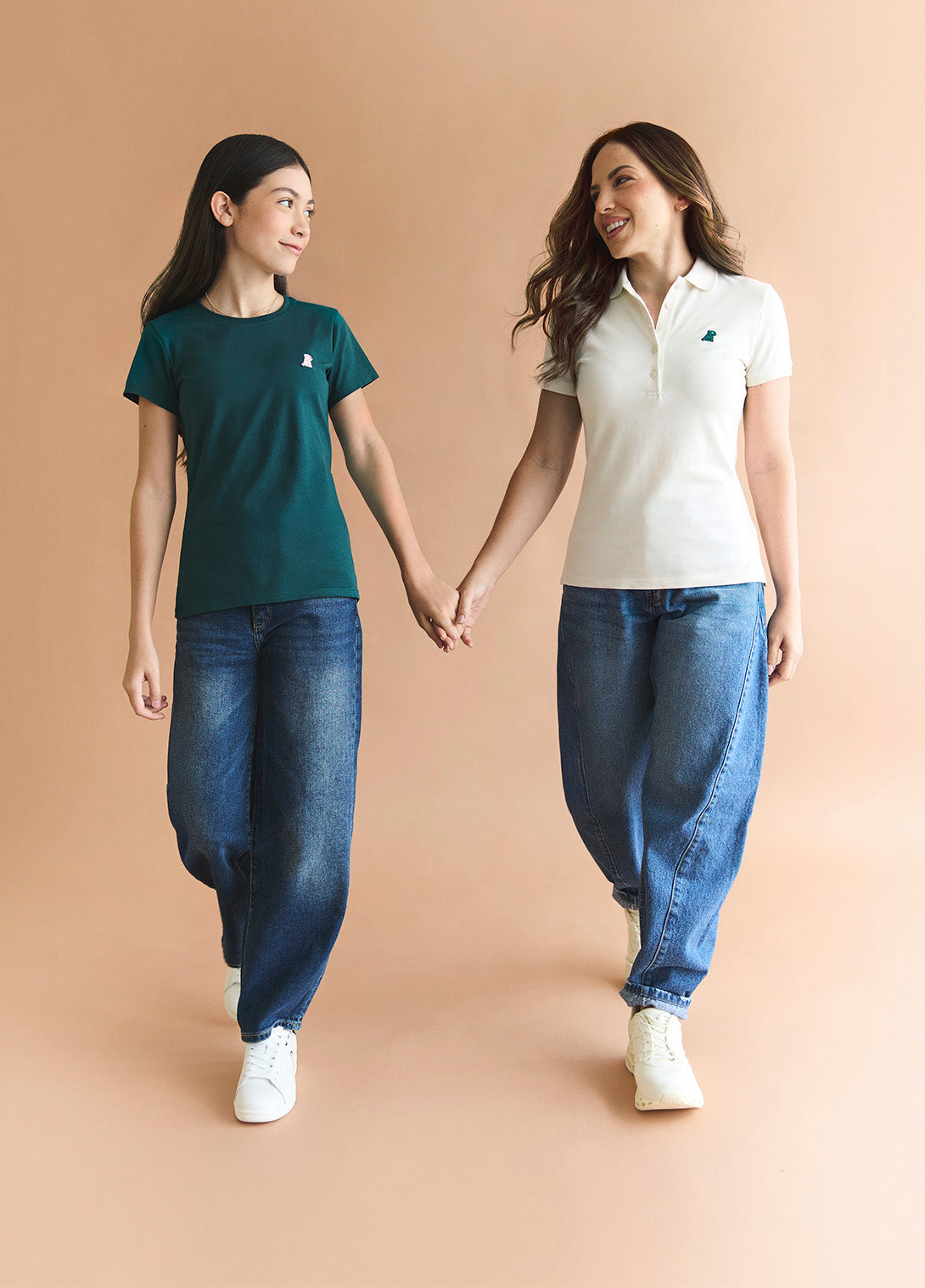 Two women holding hands against a beige background