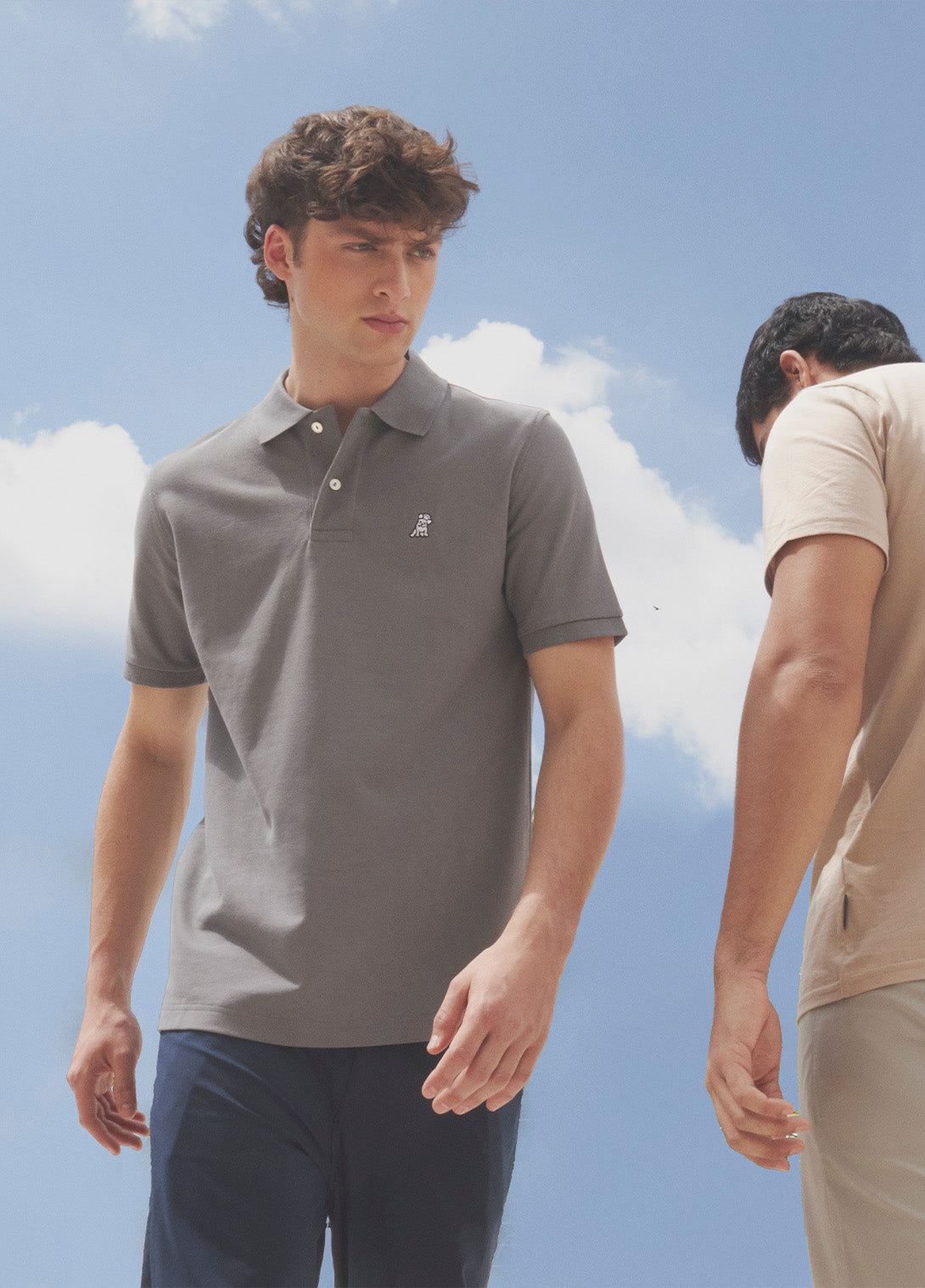 Two men wearing casual polo and t-shirts against a clear blue sky
