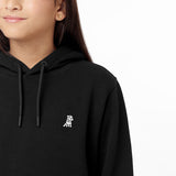 Close-up side view of the black hoodie worn by a child, focusing on the chest area with the embroidered dog logo