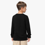 A young boy with short brown hair is shown from the back, wearing a black oversized long-sleeve sweatshirt with wide cuffs. The sweatshirt has a relaxed fit and extends slightly past his waist. He is also wearing beige pants. His head is slightly turned to the side, showing a partial profile. The background is plain white.