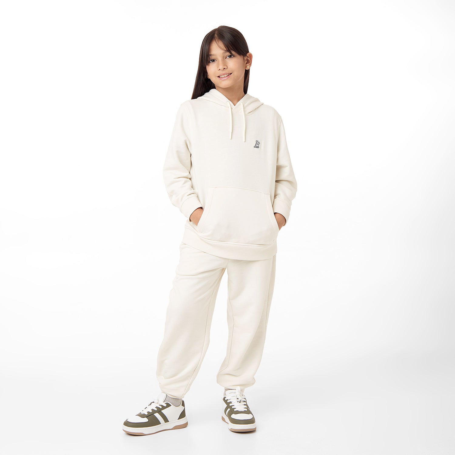  Full-body view of a child wearing the cream-colored hoodie paired with matching jogger pants, styled with sneakers and standing casually.